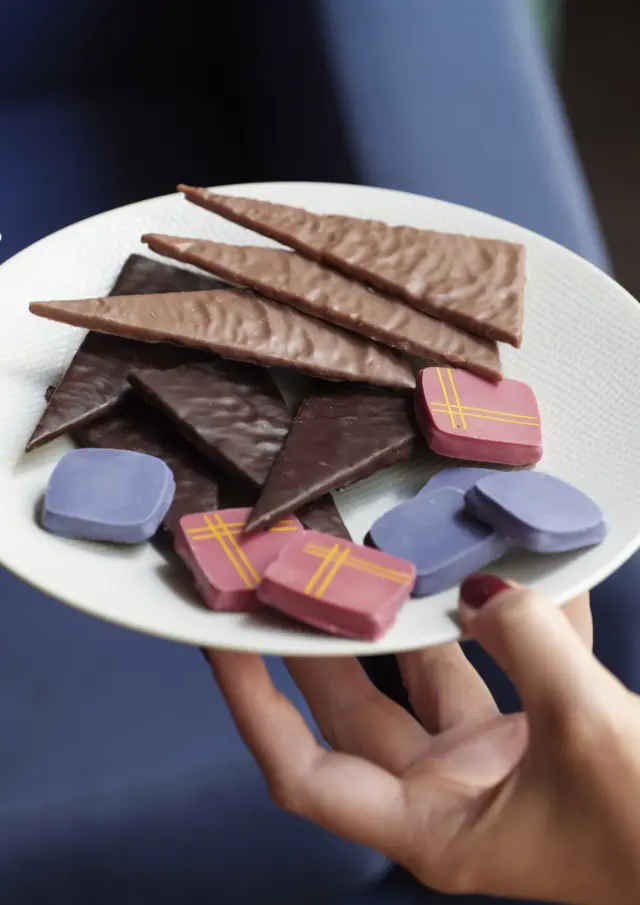 Assiette pleine de chocolats, une main la porte et une main se sert