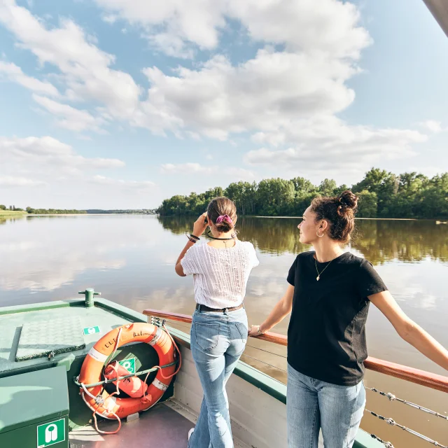 Deux jeunes femmes observant les oiseaux à la jumelles à l'avant d'un bateau sur la Loire