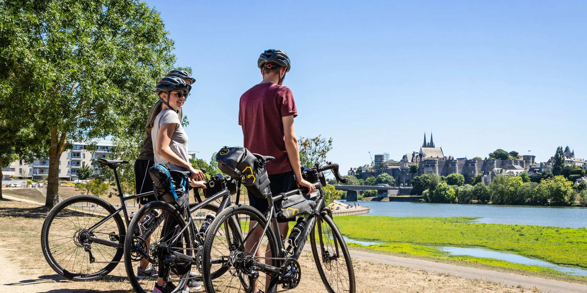 Trois personnes en vélo Gravel en face du château d'Angers