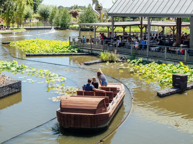 Plan large des barques du parc avec des personnes dedans, le gros ballon jaune de Terra en vol à l'arrière plan