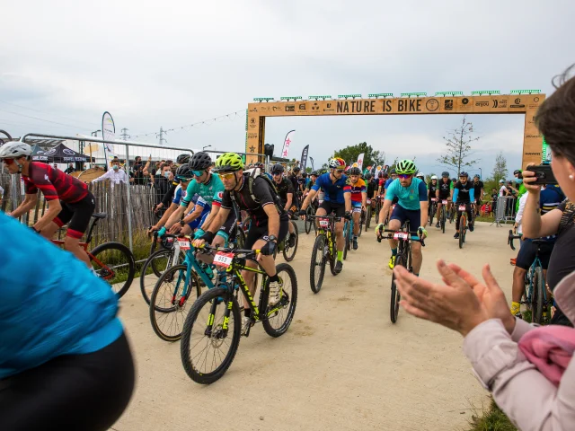 Départ de l'épreuve de gravel, personnes sur les côtés en train d'applaudir les cyclistes