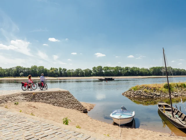 Couple arrêté à vélo au second plan regardant passer sur la Loire une toue