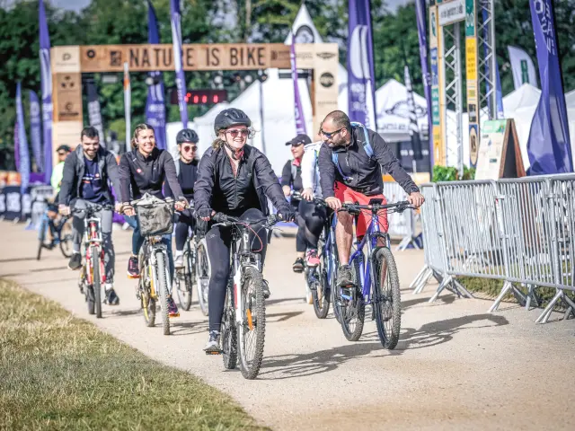 plusieurs personnes partent à vélo sous l'arche de l'événement