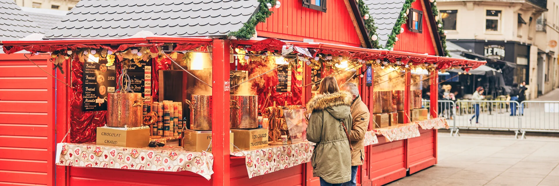 Deux personnes devant un chalet de Noël place du Ralliement