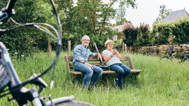 Couple de seniors assis sur un banc, un bout d'un vélo flou au premier plan