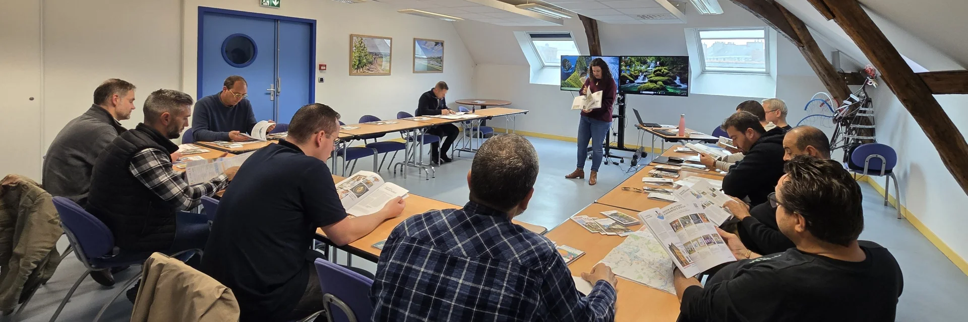 Personnes assises dans une salle de réunion, face à deux écrans allumés