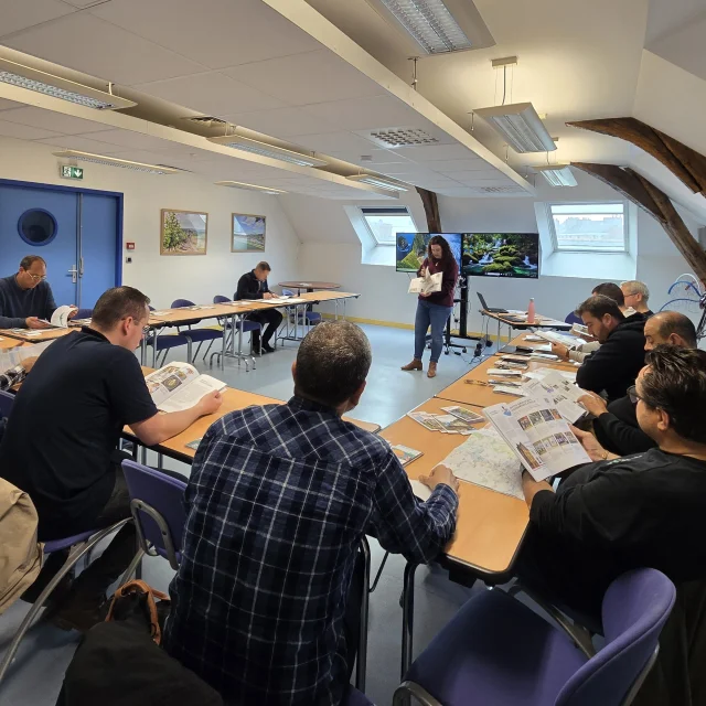 Personnes assises dans une salle de réunion, face à deux écrans allumés