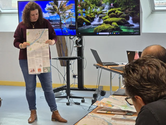 Personnes rassemblées dans une salle en U devant une animatrice qui montre un plan d'Angers