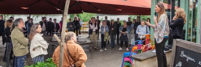 Deux personnes s'adressant à l'assemblée réunie sous un grand parasol