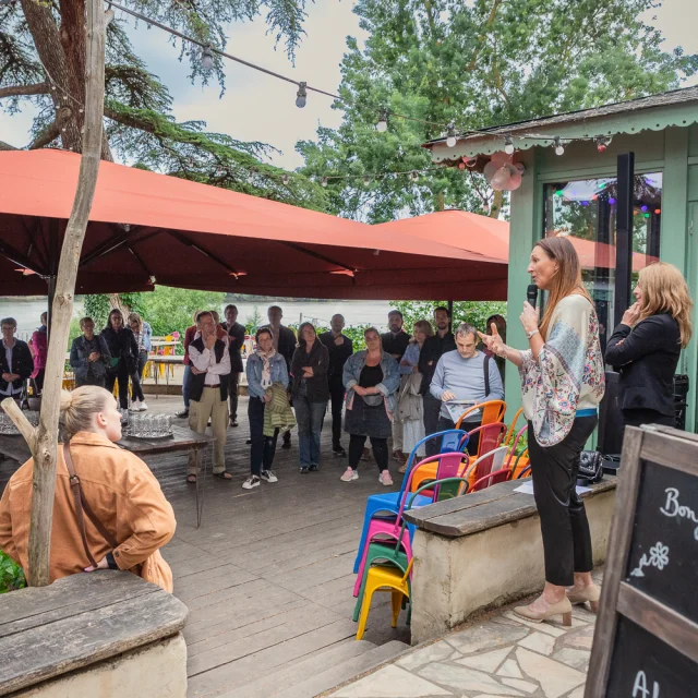 Deux personnes s'adressant à l'assemblée réunie sous un grand parasol