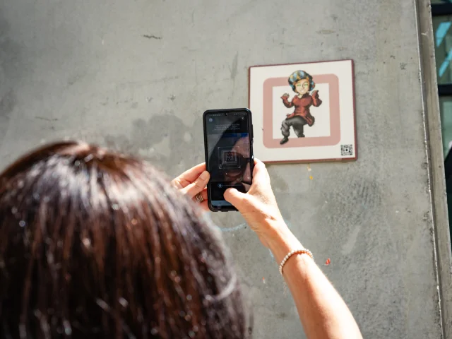 Femme scannant une plaque Cryptors au mur