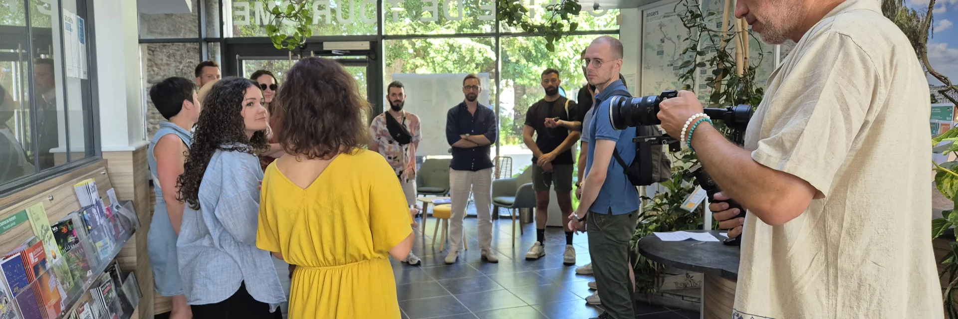 Cameraman filmant un groupe reçu à l'accueil de l'Office de tourisme