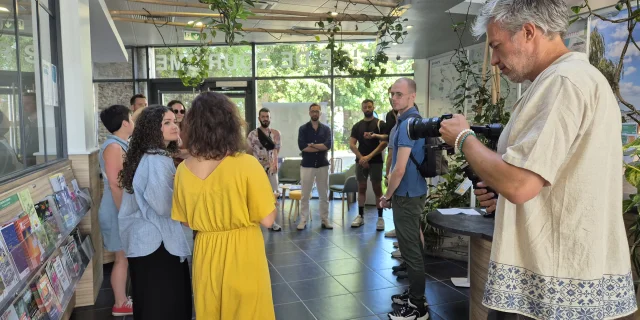 Cameraman filmant un groupe reçu à l'accueil de l'Office de tourisme