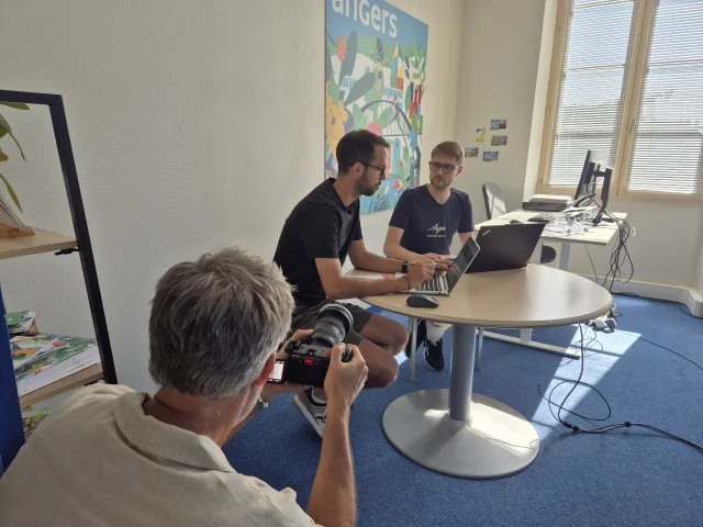 Cameraman filmant deux jeunes hommes en réunion devant un ordinateur